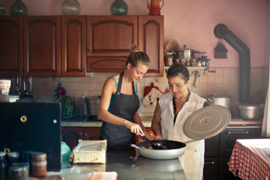 Praca opiekunki w domu seniorki - opiekunka pomaga seniorce w gotowaniu